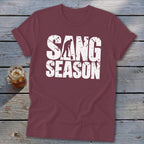 Maroon short-sleeved t-shirt with distressed white text reading SANG SEASON and a silhouette of someone digging.