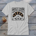 Light gray t-shirt featuring a black graphic of a woolly worm with text reading Woolly Worm Winter Prophet.