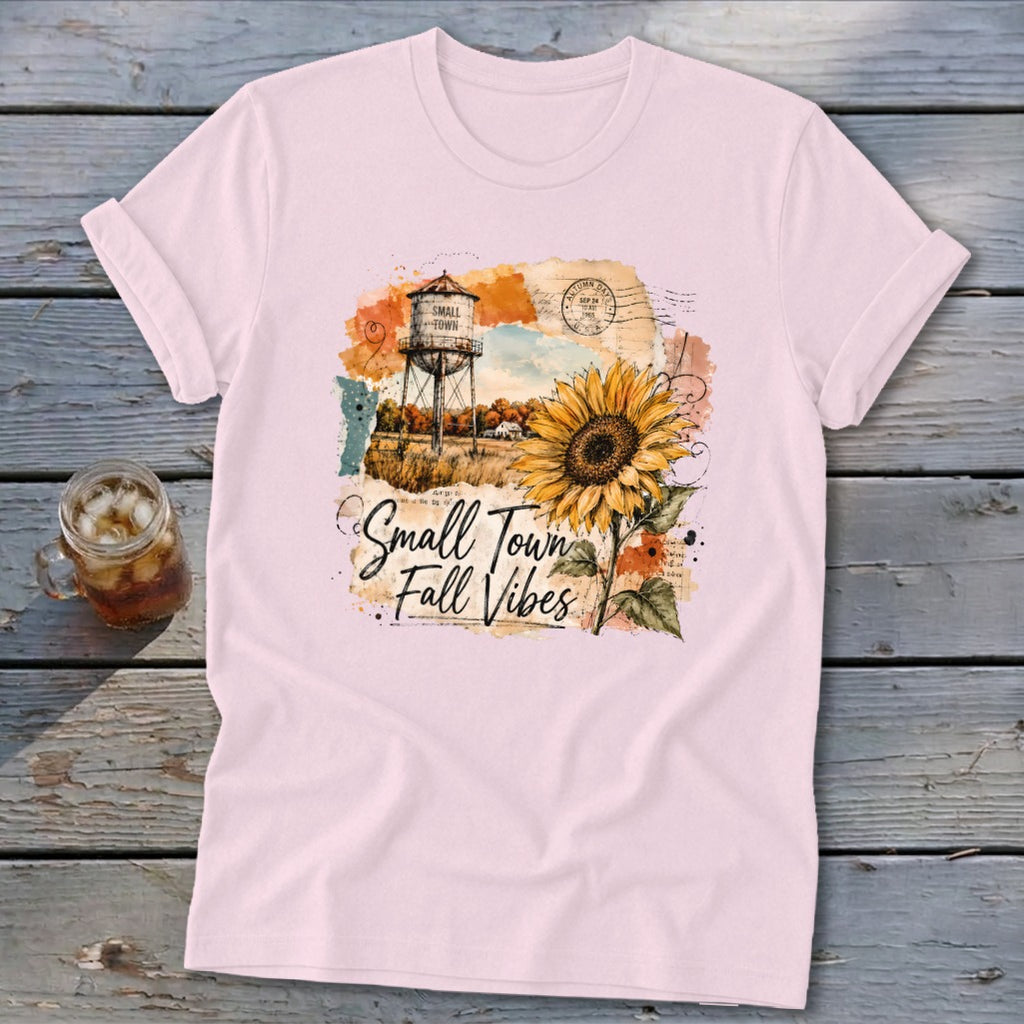 Pink t-shirt with watercolor design of sunflower, water tower, and "Small Town Fall Vibes" text.