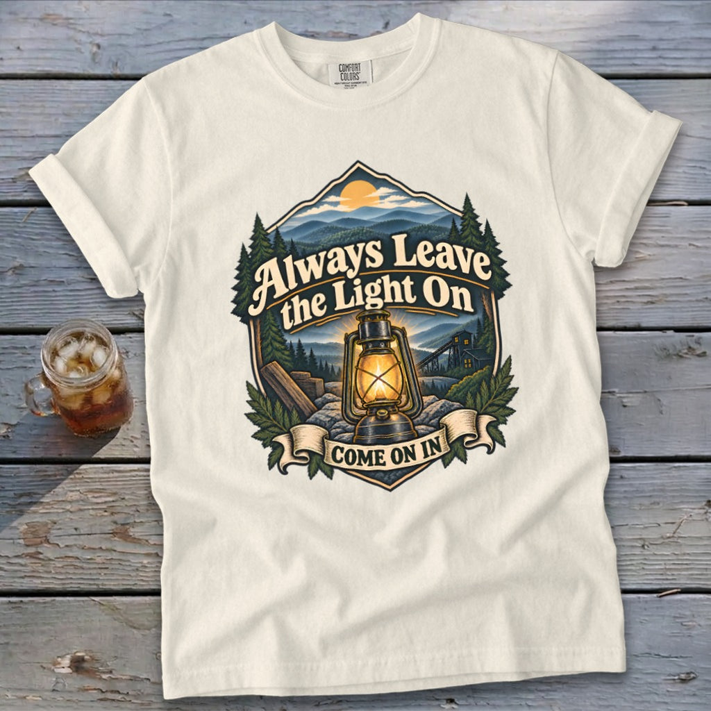 Cream t-shirt with "Always Leave the Light On Come On In" graphic featuring a lantern and landscape.