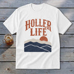 A white t-shirt featuring a retro graphic of mountains, a setting sun, and the text HOLLER LIFE.
