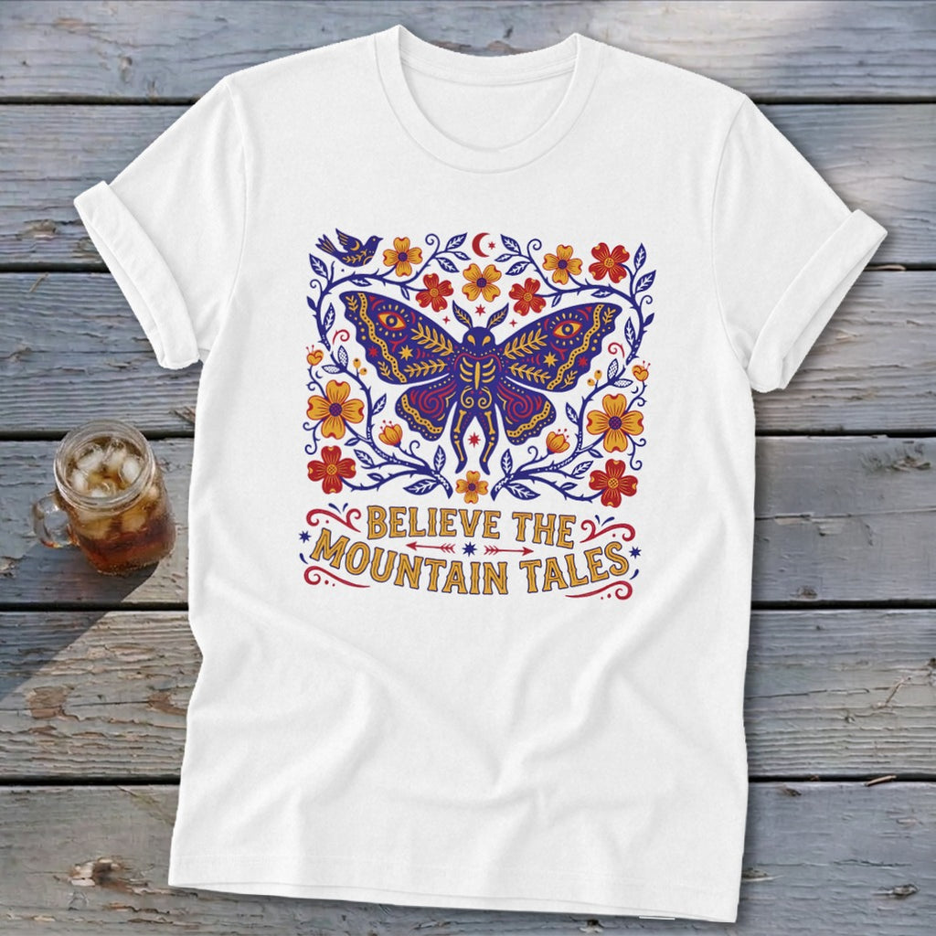White t-shirt with a purple moth design and the text "Believe the Mountain Tales".