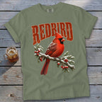 Olive green t-shirt featuring a graphic of a red cardinal on a snowy branch with red text above it.