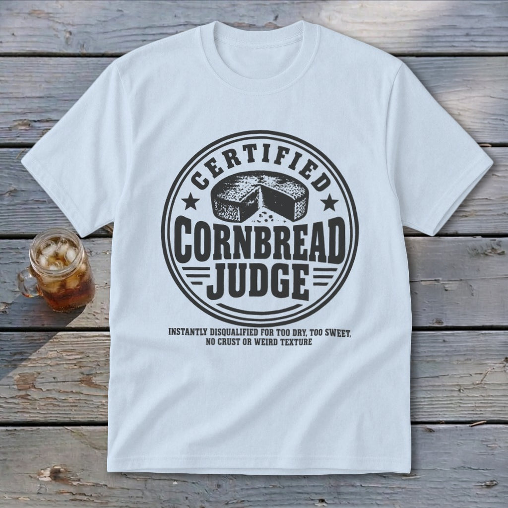 A light blue t-shirt printed with a circular badge reading Certified Cornbread Judge above text about disqualification.