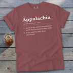A mauve t-shirt laying on a wooden surface displays white text defining Appalachia.