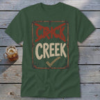 Green t-shirt with distressed sign graphic that says "CRICK" crossed out and "CREEK" with a checkmark.