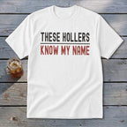 White t-shirt with black and red text reading "THESE HOLLERS KNOW MY NAME".
