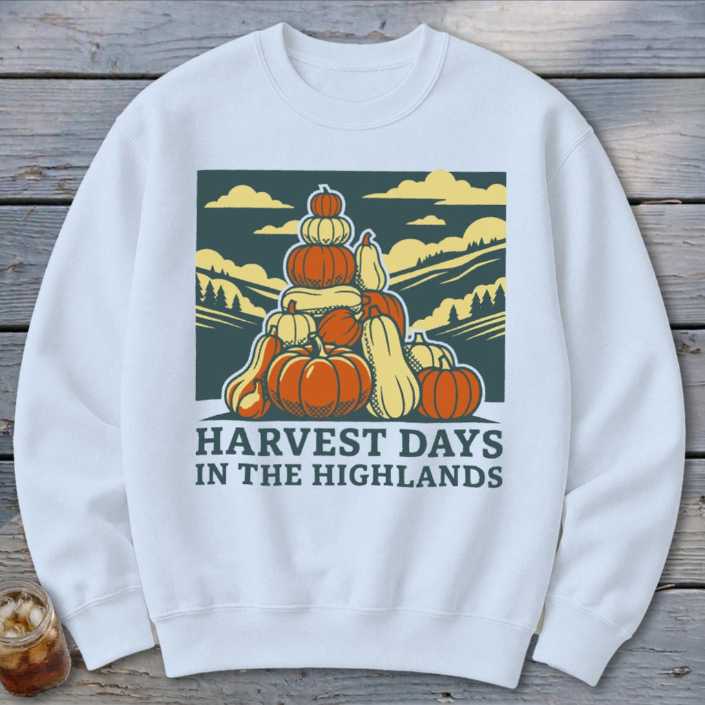 A white crewneck sweatshirt featuring a graphic of a large stack of pumpkins with the text Harvest Days in the Highlands.