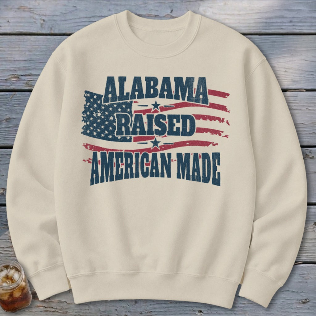 Cream sweatshirt with distressed "Alabama Raised American Made" text over a US flag design.