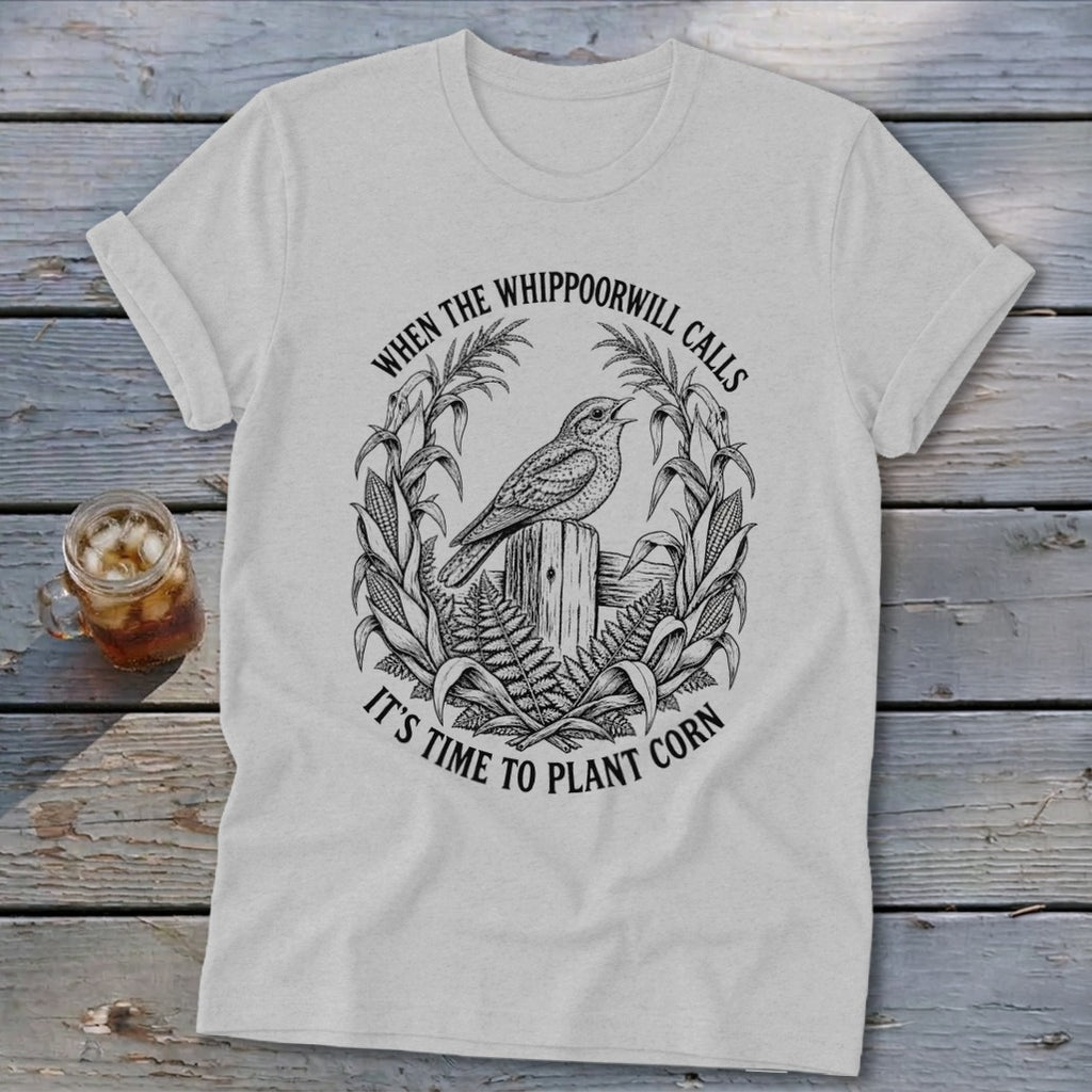Light gray t-shirt with a black vintage illustration of a bird on a fence post, surrounded by corn stalks.