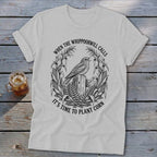 Light gray t-shirt with a black vintage illustration of a bird on a fence post, surrounded by corn stalks.