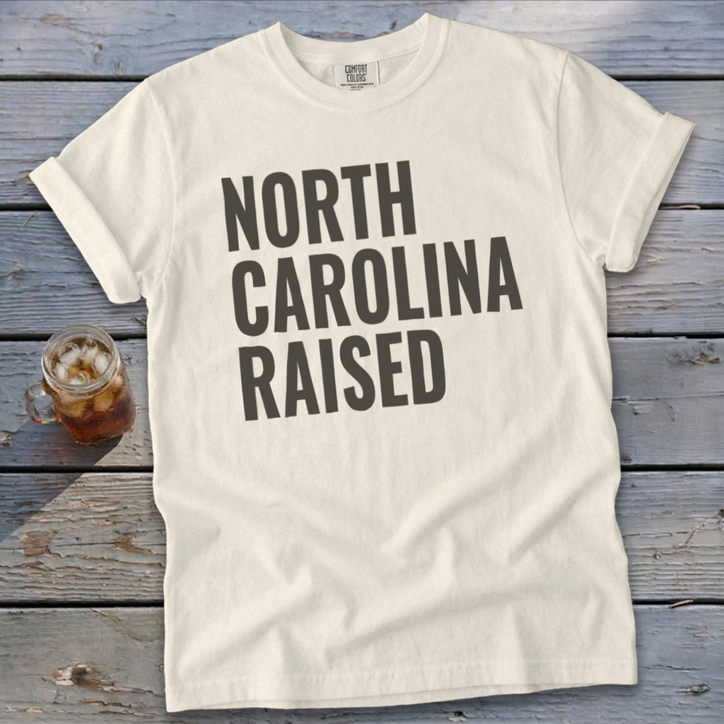 Cream t-shirt with "North Carolina Raised" text in dark gray lettering.