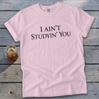 Pink Comfort Colors t-shirt with black text "I AIN'T STUDYIN' YOU".