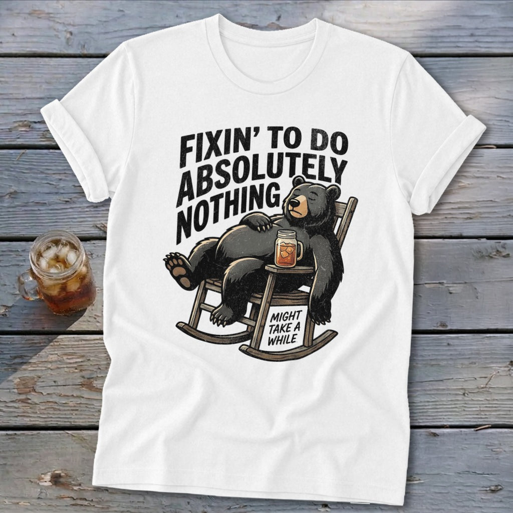 White t-shirt with a graphic of a black bear relaxing in a rocking chair, accompanied by text.