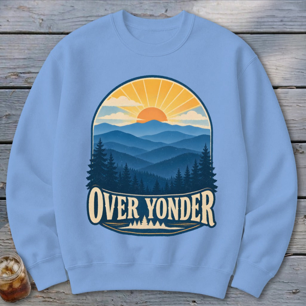 Light blue crewneck sweatshirt featuring a retro graphic of mountains, pine trees, and a rising sun with the text Over Yonder.