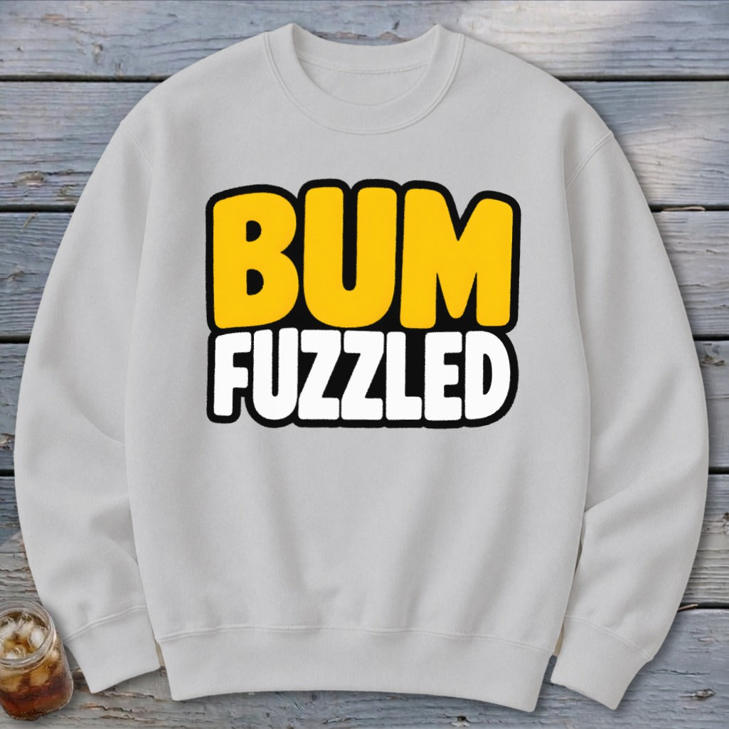 A light gray crewneck sweatshirt displays the text BUM FUZZLED in bold, uppercase cartoon letters centered on the chest.