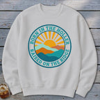 A white crewneck sweatshirt features a circular graphic with mountains, a rising sun, and the text BORN IN THE HOLLER RAISED ON THE RIDGE.