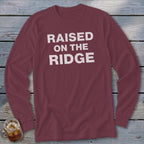 Maroon long-sleeve t-shirt with white text "RAISED ON THE RIDGE".
