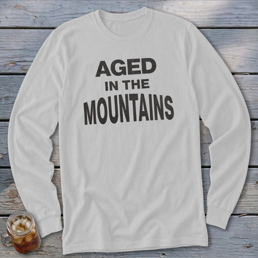 White long-sleeve shirt with "AGED IN THE MOUNTAINS" printed in black text.