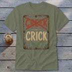 Olive green t-shirt with distressed sign graphic reading "CRICK" with a checkmark and "CREEK" crossed out.