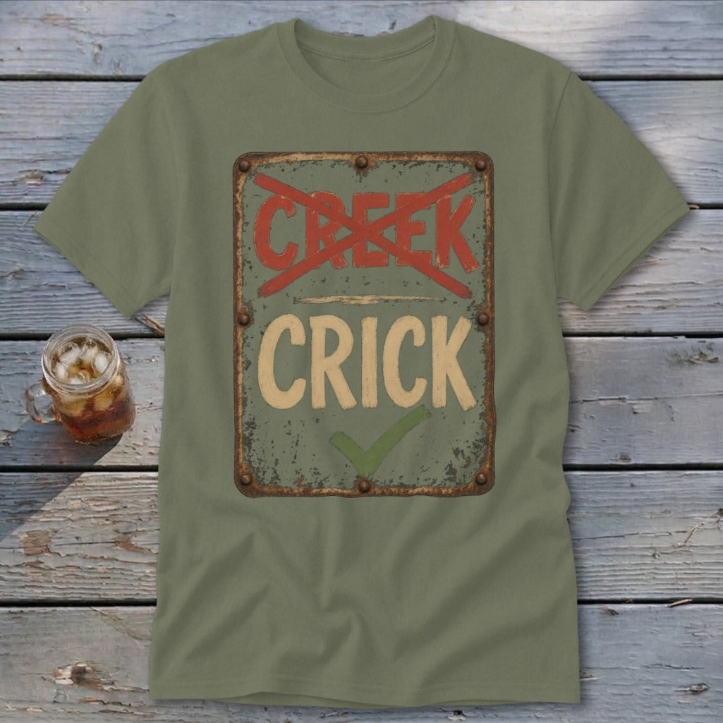 Olive green t-shirt with distressed sign graphic reading "CRICK" with a checkmark and "CREEK" crossed out.