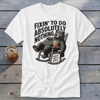 White t-shirt featuring a cartoon bear relaxing in a rocking chair with text that reads Fixin to do absolutely nothing might take a while.