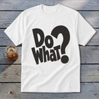 A white t-shirt featuring the black text Do What? spread across the chest, laid flat on a rustic wooden surface next to a glass of iced tea.