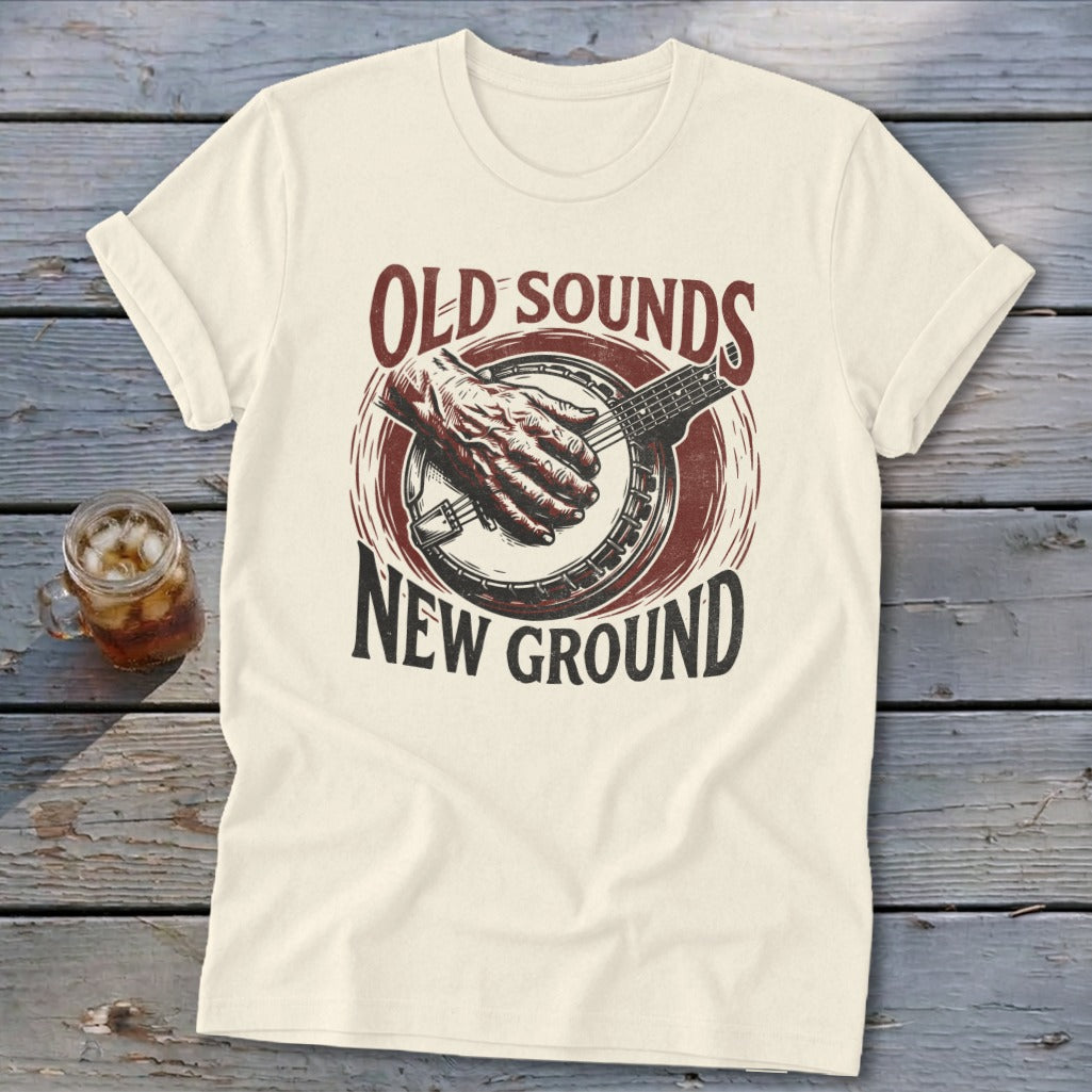 Cream crewneck t-shirt with a vintage-style graphic of a banjo player and text reading Old Sounds New Ground.