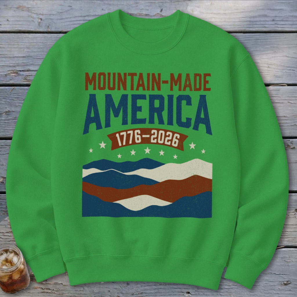 Green crewneck sweatshirt featuring a Mountain Made America 1776-2026 design with wavy stripes and stars.