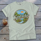 Light green t-shirt with circular "Kentucky" graphic featuring a scenic landscape and deer.