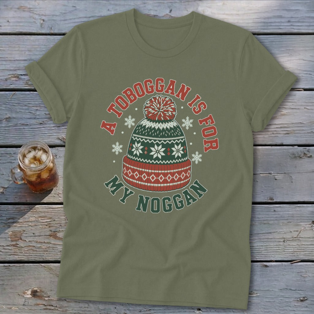 An olive green t-shirt with rolled sleeves features a graphic of a winter hat and the text A Toboggan Is For My Noggan.