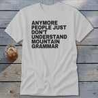 White t-shirt with black text that reads "anymore people just don't understand mountain grammar."
