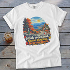 White t-shirt with autumn mountain overlook graphic and text: "Peak weekend. Same playlist. New overlook."