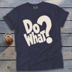 Dark blue crewneck t-shirt featuring bold, cream-colored text reading "Do What?" on a rustic wooden background.