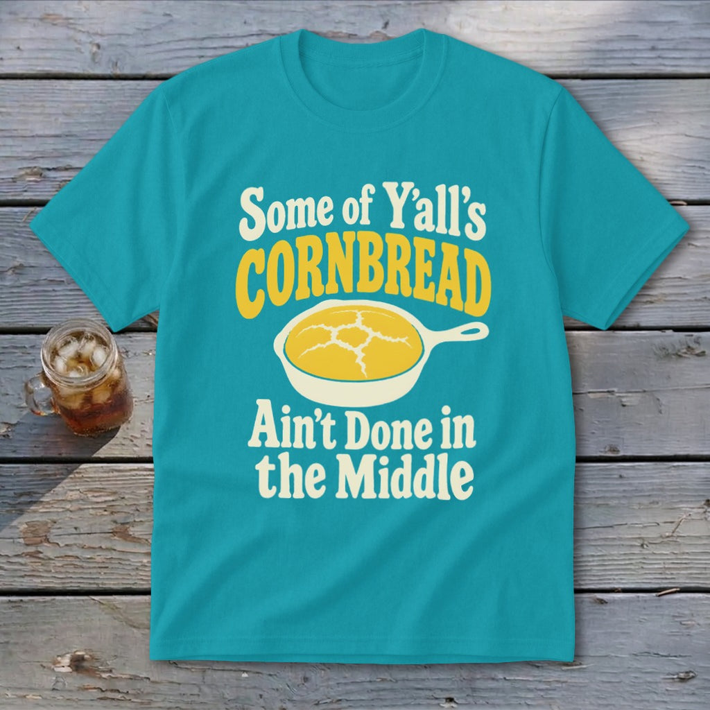 A turquoise t-shirt with the text "Some of Y'all's Cornbread Ain't Done in the Middle" and a skillet graphic.