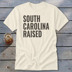 Cream t-shirt with "SOUTH CAROLINA RAISED" in dark text.