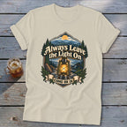 Cream t-shirt with graphic of lantern, mountains, trees, and text "Always Leave the Light On COME ON IN."