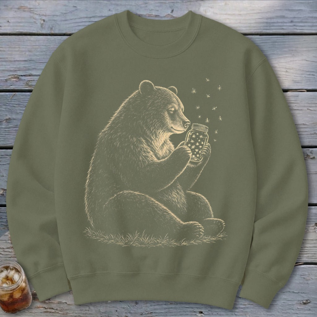 Bear holding a jar of stars with fireflies around, on a green sweatshirt.