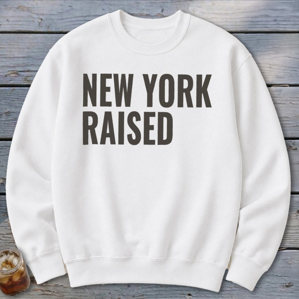 White sweatshirt with bold black text "NEW YORK RAISED" across the chest.