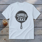 White t-shirt with black text and cast iron skillet graphic that reads "Cornbread Ain't Cake."