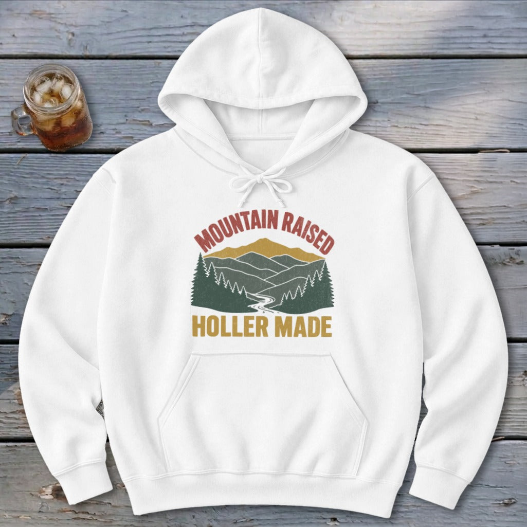 A white hoodie featuring a graphic with mountains, trees, and the text MOUNTAIN RAISED HOLLER MADE.