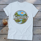 White t-shirt with circular Kentucky landscape graphic featuring deer, river, and mountains.