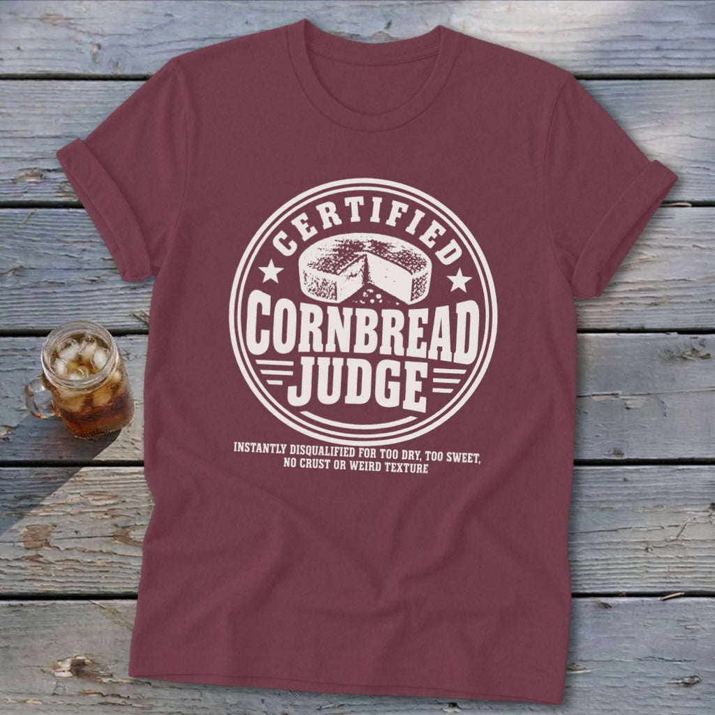 Maroon t-shirt with a white circular graphic featuring the text Certified Cornbread Judge and a cornbread loaf.