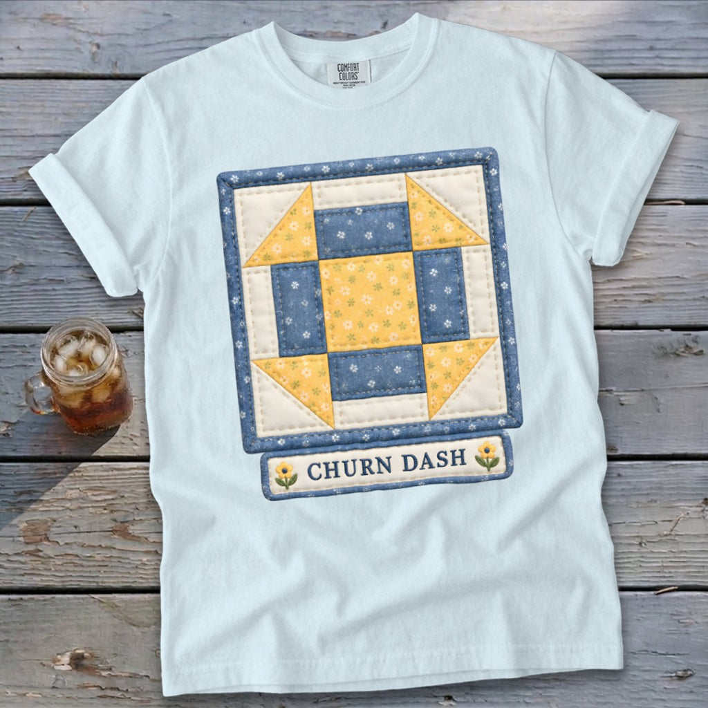 Light blue t-shirt with a quilted "Churn Dash" block design and sunflowers.