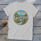 White t-shirt with circular Georgia mountain landscape graphic and deer.