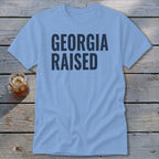 Light blue t-shirt with "GEORGIA RAISED" in navy text.