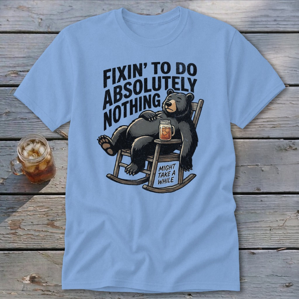Light blue t-shirt featuring a cartoon black bear relaxing in a rocking chair with a drink.