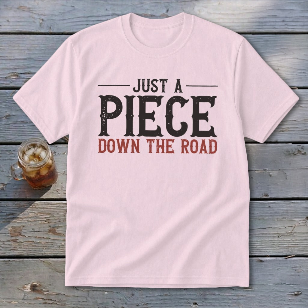 Pink t-shirt with "JUST A PIECE DOWN THE ROAD" graphic.