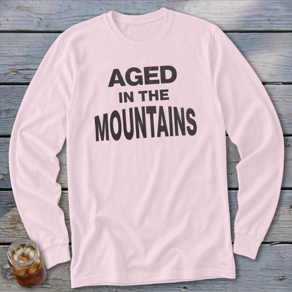 Pink long-sleeve t-shirt with "AGED IN THE MOUNTAINS" text in black.