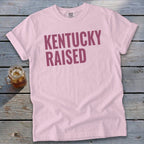 Pink t-shirt with maroon "Kentucky Raised" text and a drink.